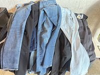 Pile of assorted jeans and pants on table