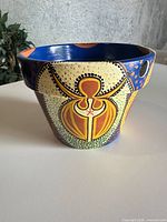 front view of hand-painted ceramic flower pot showing cream panel with yellow and brown motif