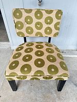 Front view of armless chair showing patterned upholstery and button-tufted back