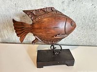 Full view of carved wooden fish on stand front left