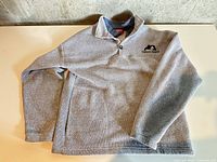 Front view of grey fleece sweater laid flat