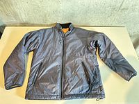 Front view of grey MEC insulated jacket laid flat showing zip front and pockets