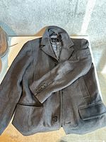 Full view of dark grey RW&CO men’s medium coat laid flat