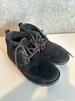 Side view of both black suede Ugg boots showing uppers, laces and soles
