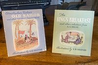 Front covers of both A.A. Milne books with dust jackets displayed on stands