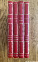 Spines of all four red gilt-decorated volumes