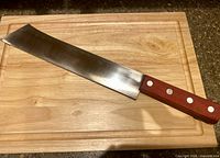 Full view of knife on cutting board showing blade shape and handle