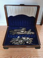 Open chest showing interior lining and contents: flatware and souvenir spoons
