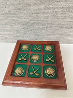 angled view of board showing brass golf ball and club pieces in green felt squares