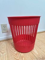 Front view of red slotted waste basket