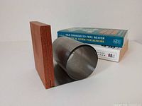 Bookend angled showing teak block upright and stainless steel cylindrical support on base