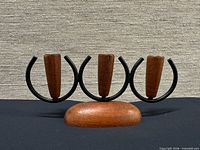 Front view showing teak base, three black steel rings and teak candle cups