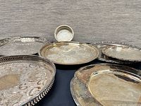 Group view showing seven silver-plated trays in various shapes and rim styles
