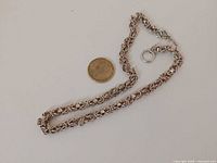 Necklace laid out with coin for scale showing full length and chain design