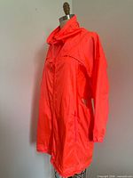 Side view of neon orangey-pink parka on dress form
