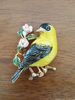 Front view of goldfinch enamel brooch showing colors, design, floral accent