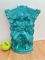 Full view of turquoise glazed Hulk sculpture beside tennis ball