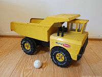 Full view of yellow Tonka dump truck with golf ball for scale