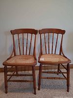 Front view of both chairs showing spindle backs and cane seats