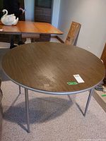 Top view of round vinyl woodgrain card table with metal legs