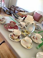 Multiple mismatched bone china cups, saucers and plate displayed on table