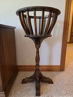 Full view of wooden fern stand next to cabinet