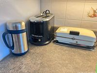 Stainless beverage container, Hamilton Beach toaster, Toastmaster griddle together on countertop