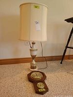 Full view of lamp with shade and barometer on floor