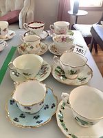 Tabletop view showing all ten matching floral bone china teacup and saucer sets