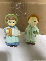 Two child figurines, accordion player and boy in coat