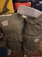 Two of the large green woven sacks with twist ties; top shows additional plastic-wrapped roll