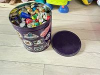 Closed purple tin with lid off to side showing exterior stickers