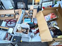 Overall lot view showing bulbs, antenna box, cables, gauge, shift knob box and wiring on table