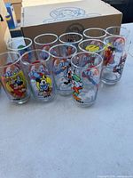 Group shot of eight Mickey Mouse glasses showing varied designs and year markings