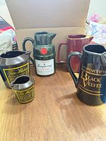 Grouping of six branded ceramic pitchers and creamers on table