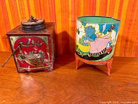 Square tin organ with crank and top disc beside cylindrical washer toy