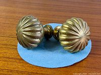 Front view of both brass ribbed knobs joined by spindle