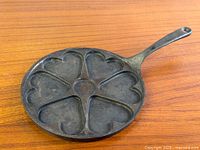 Top view of round cast iron skillet showing seven heart molds