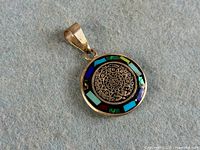 Front view of silver pendant showing Mayan calendar and multicolour inlay