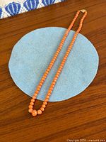Entire strand of coral beads laid flat showing graduated sizing