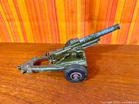 Left side view of die-cast metal toy field cannon showing overall design and paint wear
