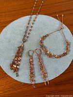 Full view of necklace, bracelet, and earrings on fabric background