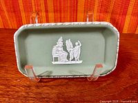 Top view showing sage green dish with white classical relief and vine border