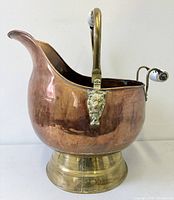 Front view showing copper body, brass base, swing handle with ceramic grip, lion head detail