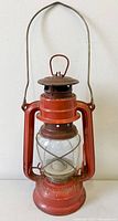 Front view of red "The Bat" No.158 railway oil lantern showing overall form and markings