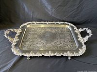Top view showing entire ornate silver tray with handles and feet