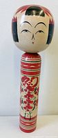 Full view of wooden kokeshi doll showing head, body, painted design