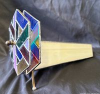 Side view showing triangular stained glass body and multicolour end wheel