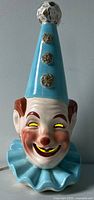 Full view of ceramic clown head lamp showing cone hat, illuminated eyes and mouth
