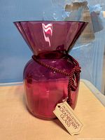 Full view of cranberry glass vase with tag attached
